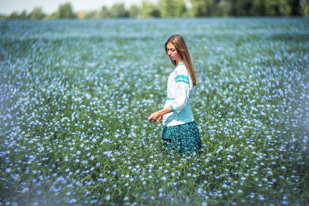 девочка в русском народном платье в цветущем поле льна