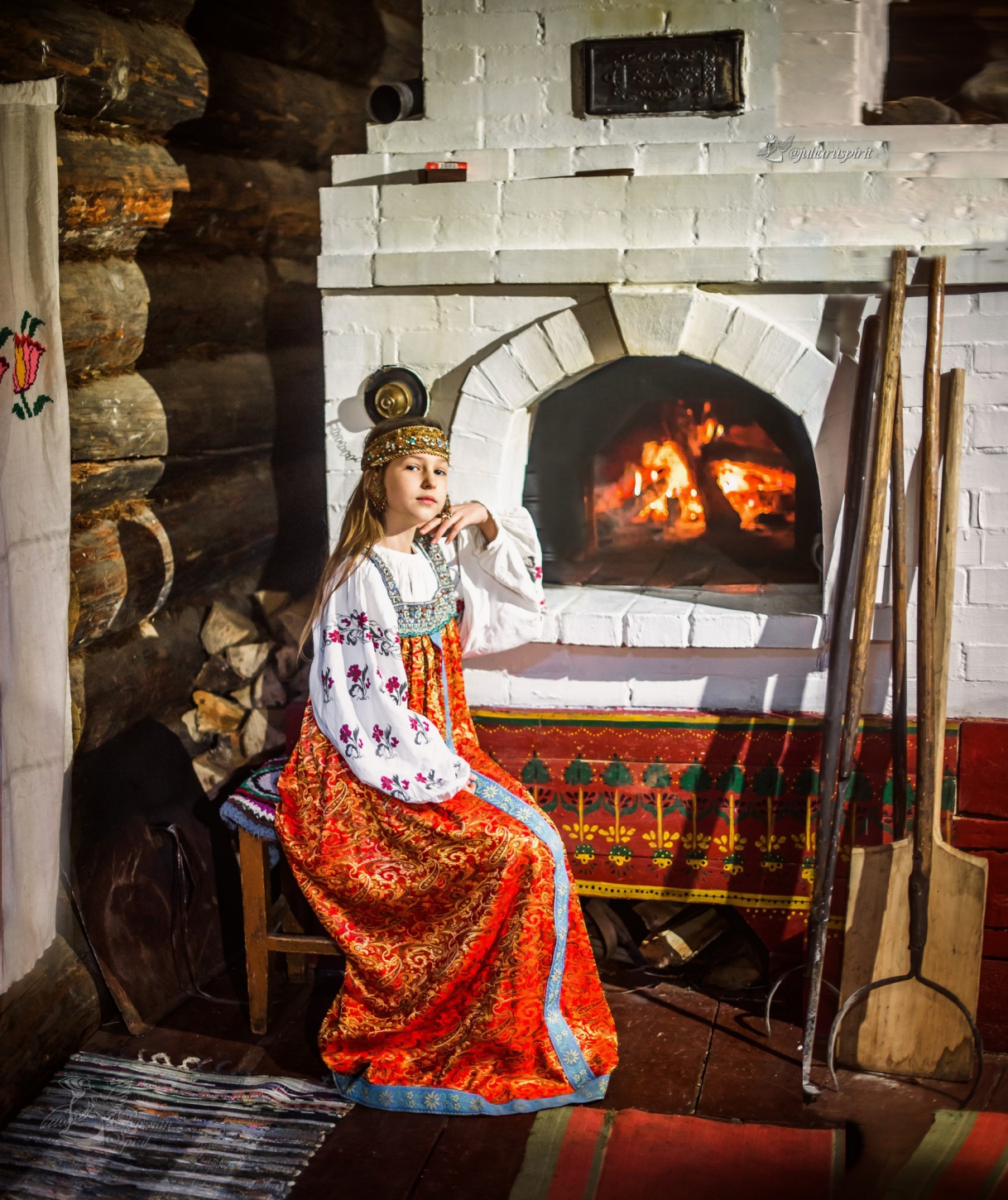 Девушка в платье в русском стиле на лавочке у настоящей русской печки