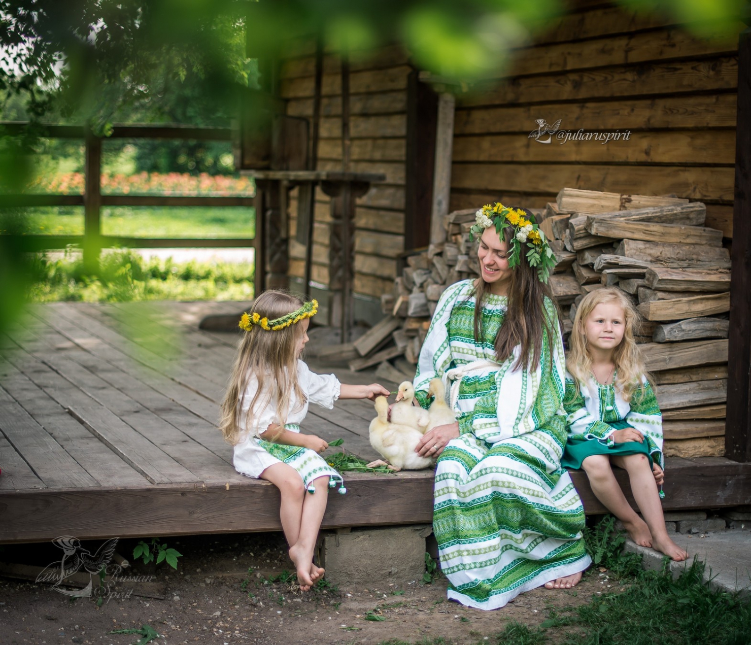 Мама с дочками в русских народных костюмах на крылечке гладят утят