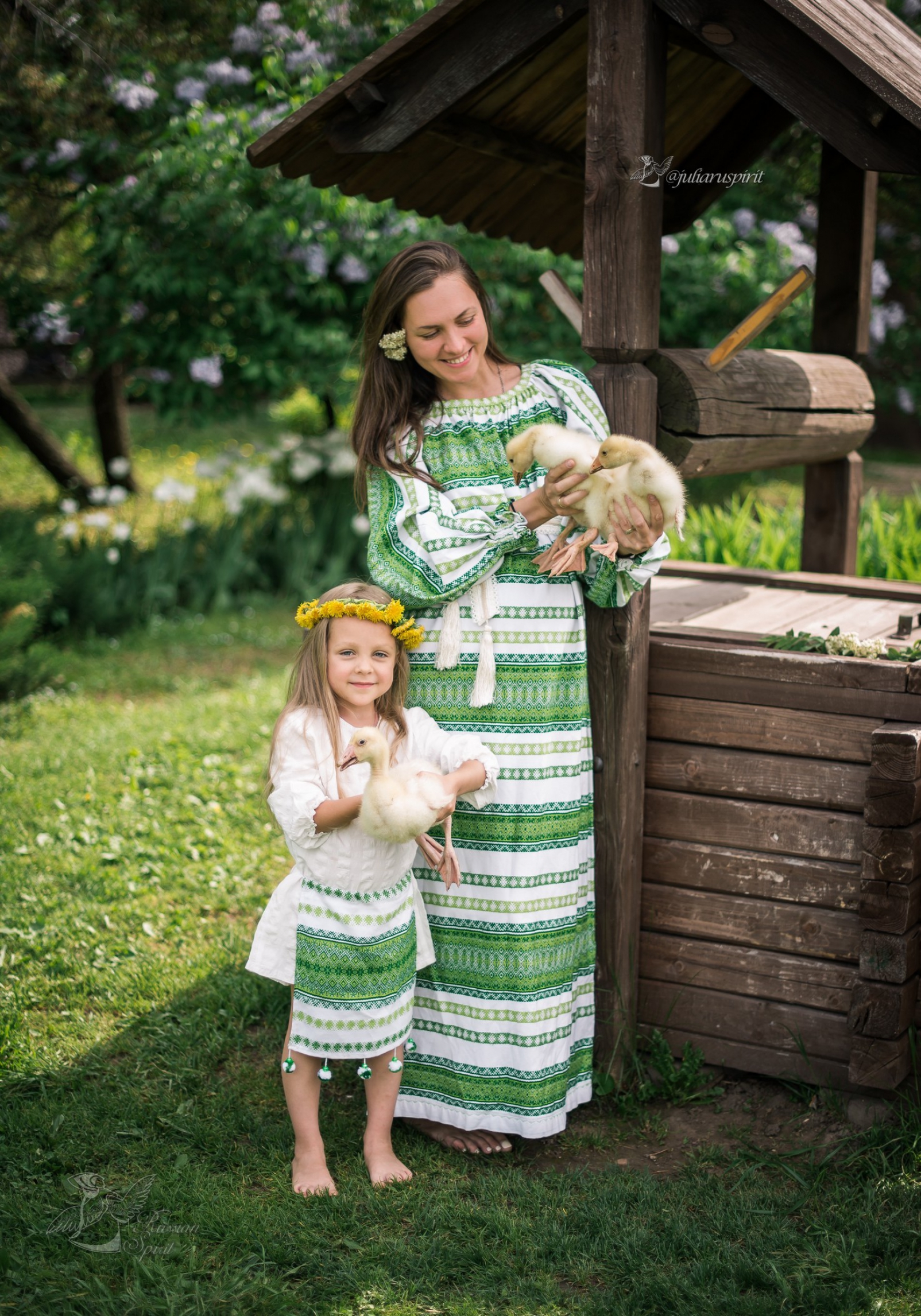Мама с дочкой в поле в национальных костюмах у колодца с утятами