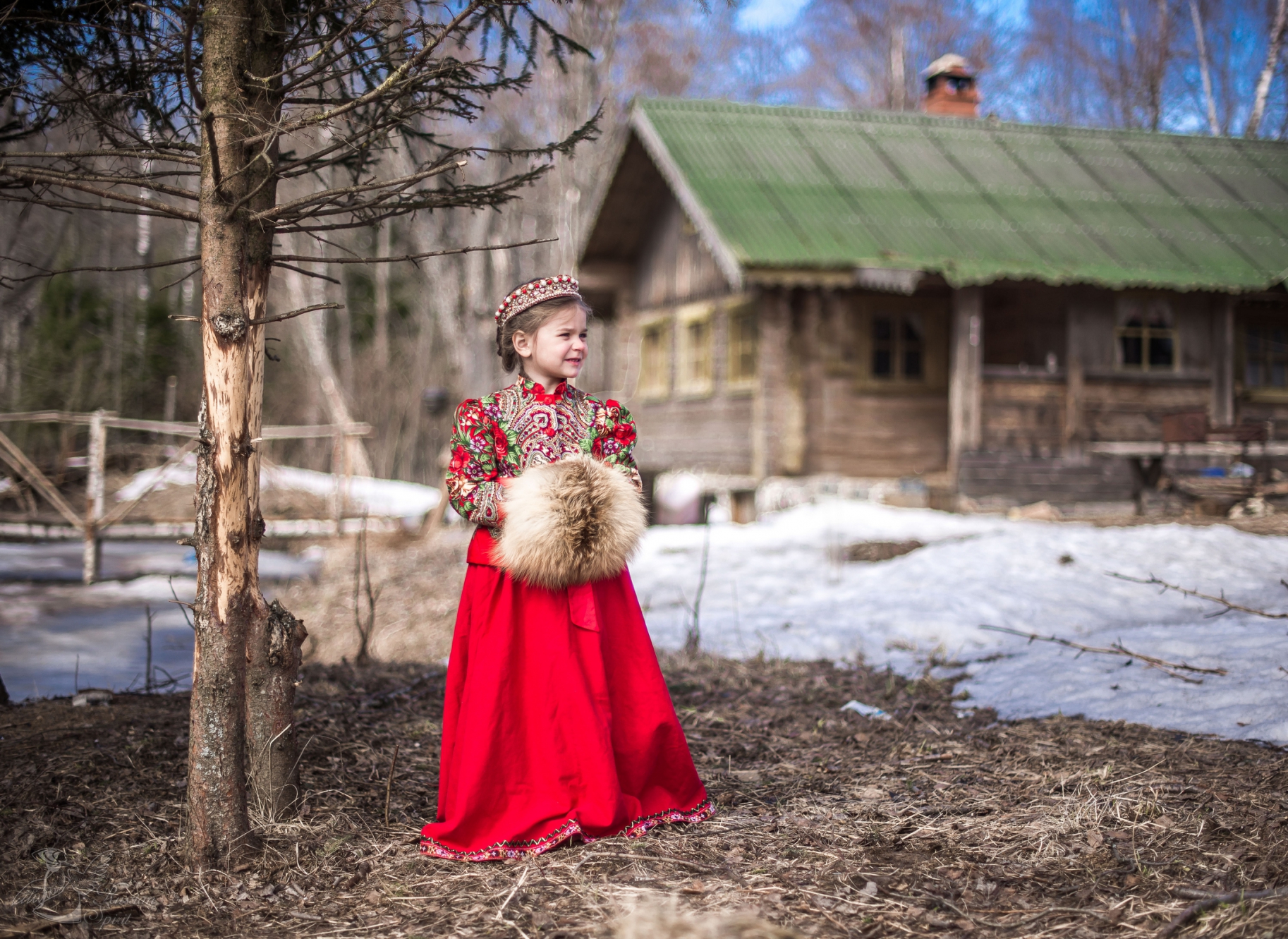 Девочка в платье в русском стиле на фоне деревенского дома