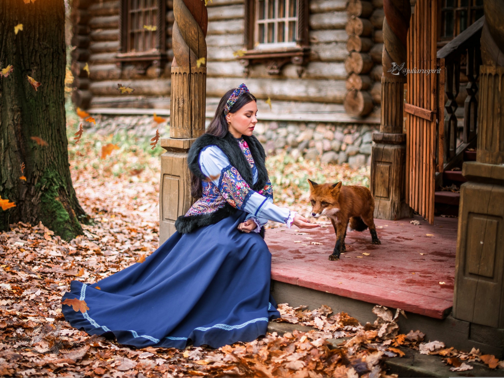 Девушка в костюме в русском стиле кормит лису на крылечке