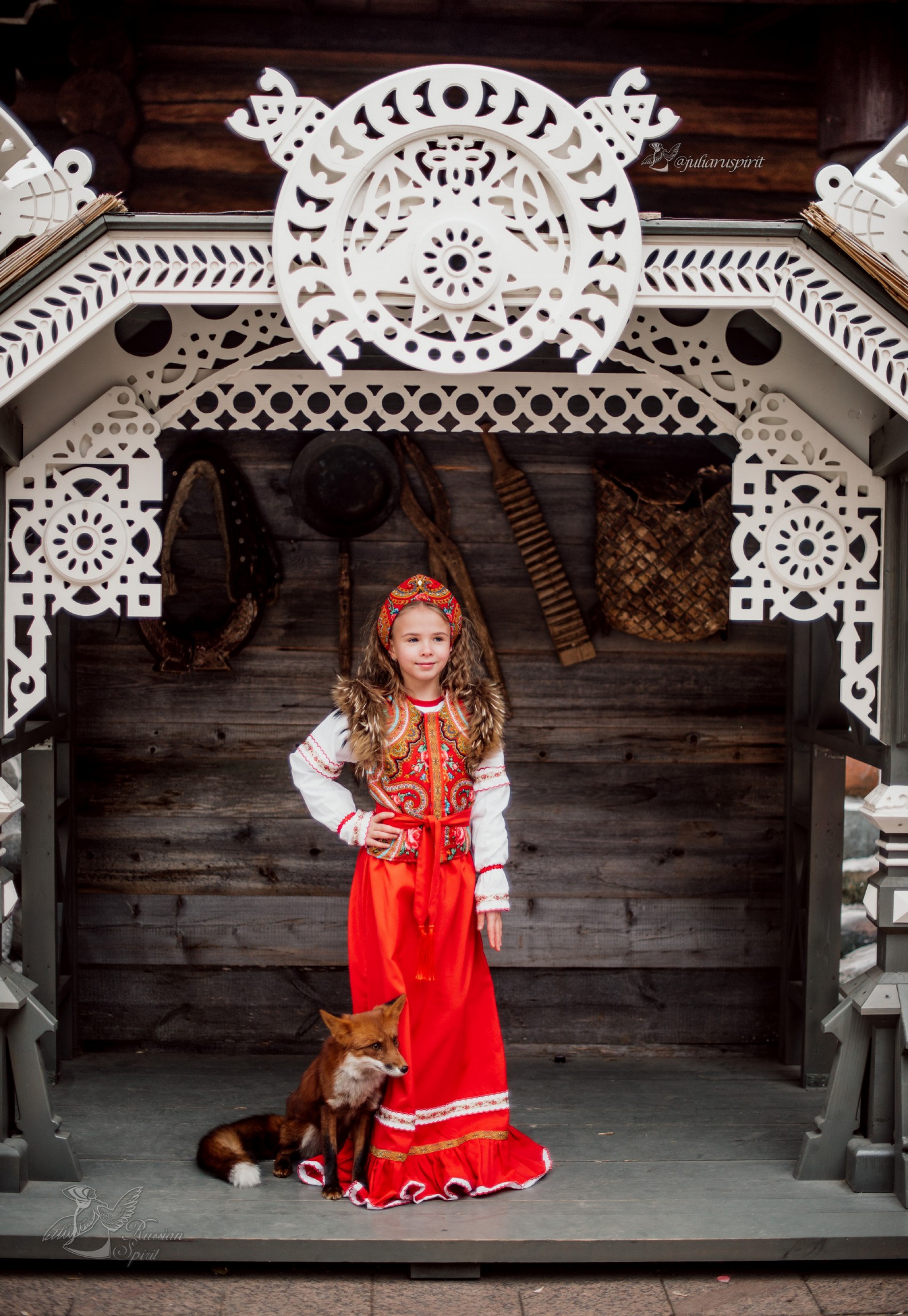 Девочка в платье в русском стиле на фоне стены дома с вырезными узорами