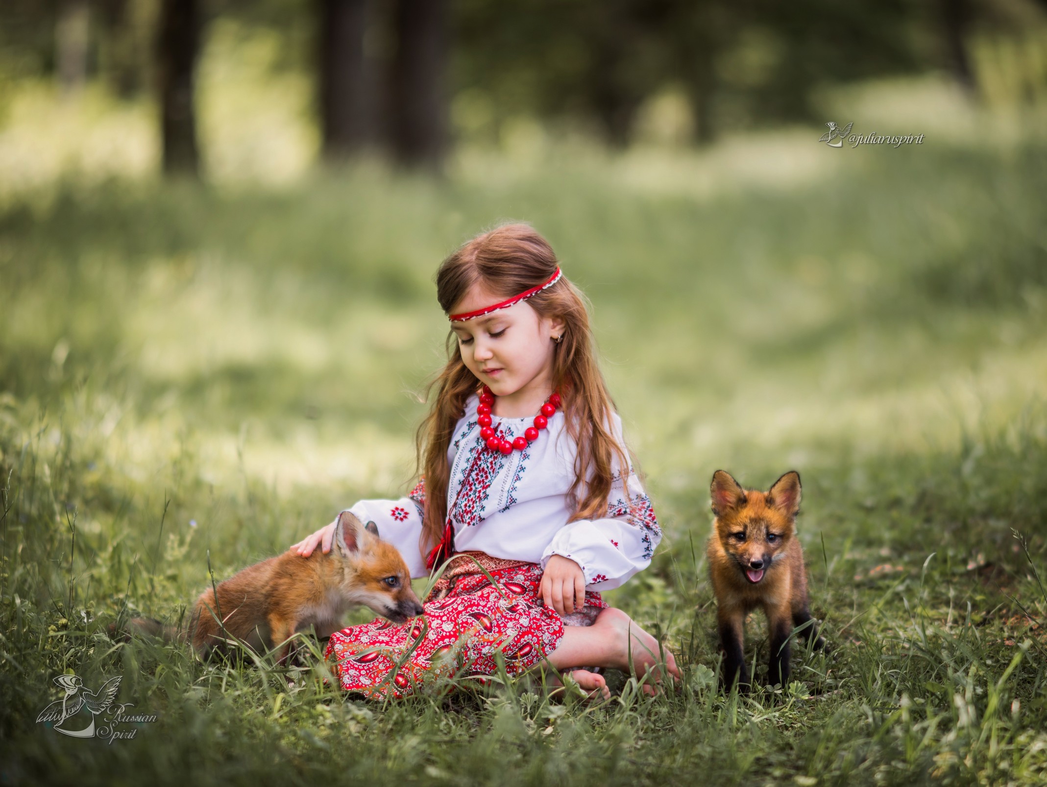 Девочка в русском народном костюме с лисятами на лужайке сидит