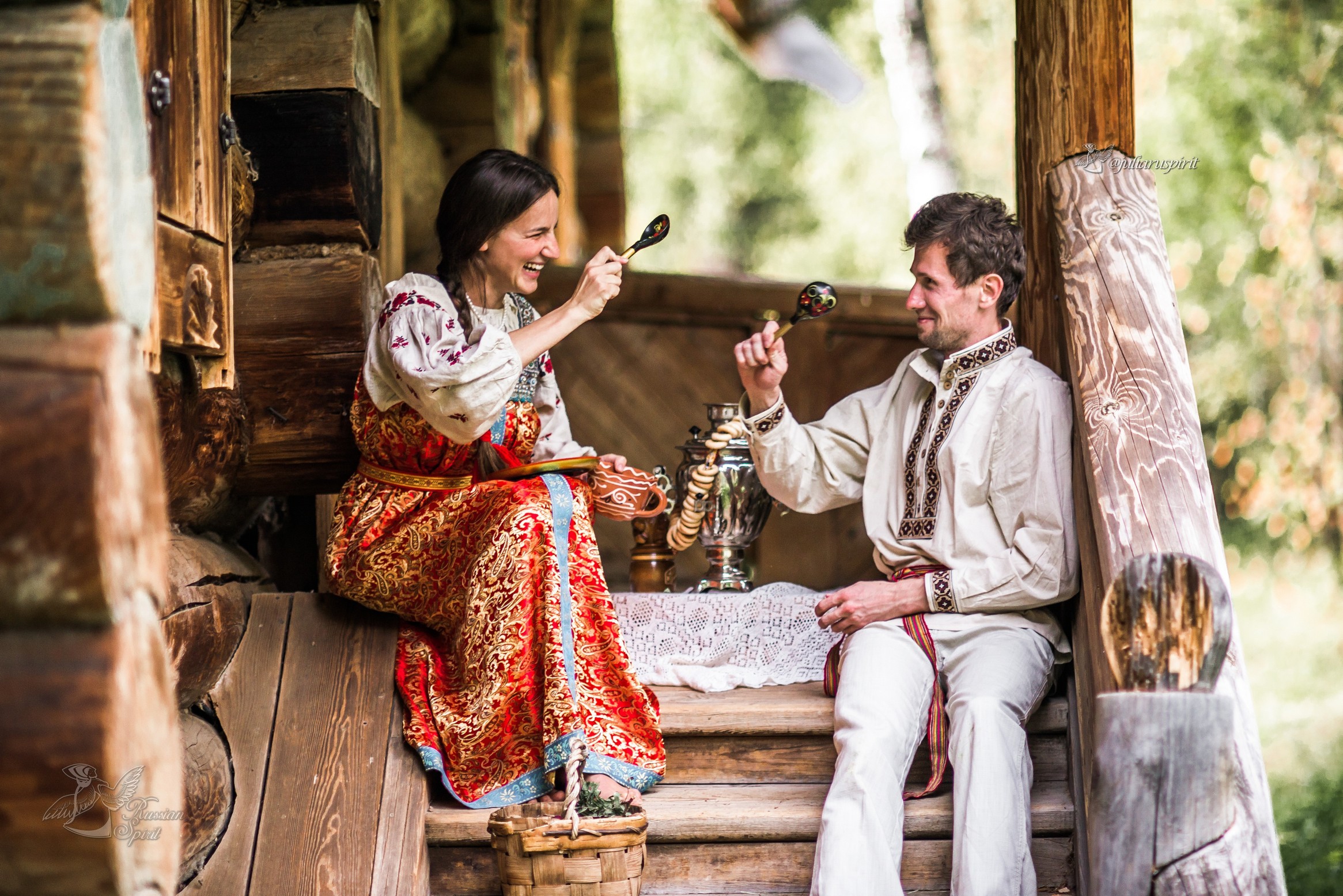 Девушка и парень пьют чай из самовара на крылечке деревянного дома в русском стиле