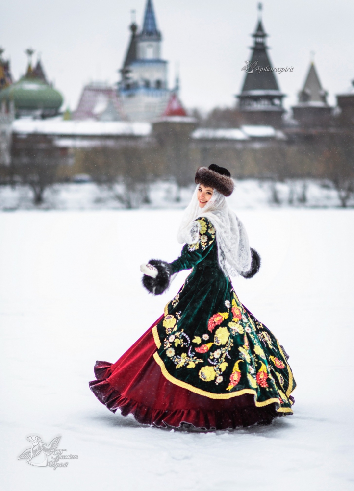 Девушка в вышитом узорами платье на фотосессии кружится на фоне кремля