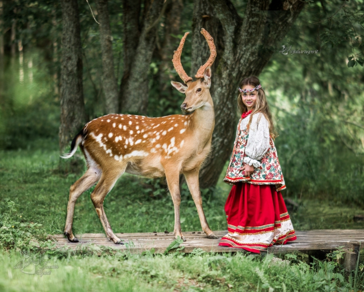 девочка в русском народном платье в лесу с оленем