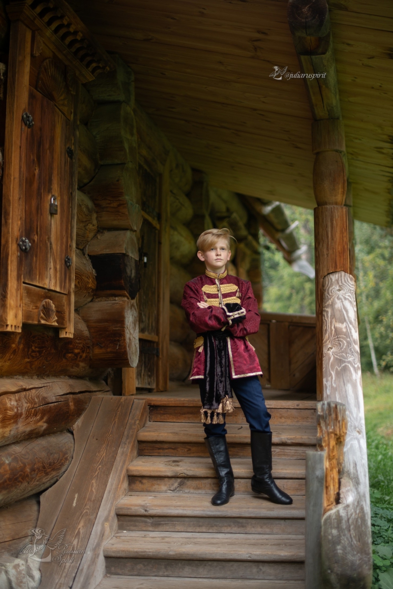 Мальчик в костюме в русском стиле на лестнице деревянного дома