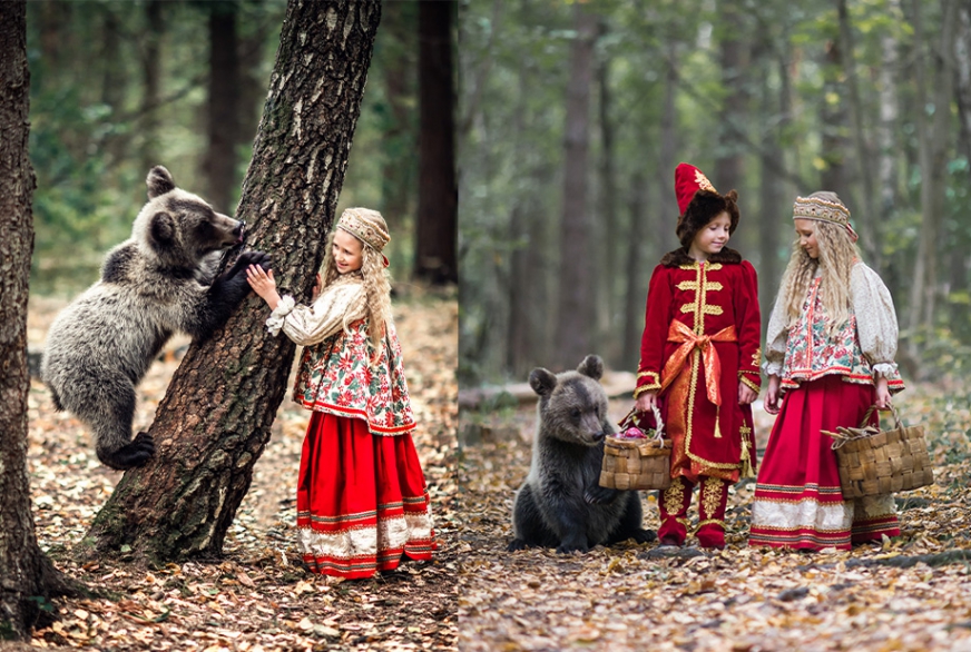 Девочка и мальчик в костюмах в русском стиле с медвежонком в лесу